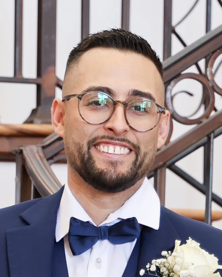 David Quintana smiling in a navy suit and bow tie
